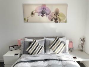 ein Schlafzimmer mit einem Bett mit gestreiften Kissen und Blumen an der Wand in der Unterkunft Bridgewater House - Private Room & Bathroom Near Etihad and CoOp Arena in Manchester