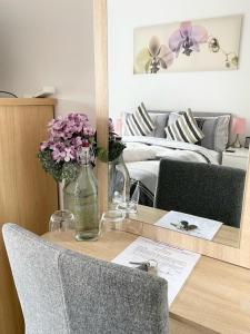 a table with a glass bottle of water and flowers on it at Bridgewater House - Private Room & Bathroom Near Etihad and CoOp Arena in Manchester