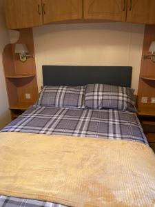 a bed with a plaid bedsheet and two pillows at Croft View in Taynuilt