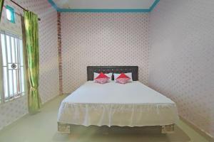 1 dormitorio con cama blanca y almohadas rojas en OYO 92002 Wisma Samudra, en Pangkajene