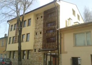 un grand bâtiment en briques avec un arbre devant lui dans l'établissement Hotel Hinovi Hvoyna, à Hvoyna