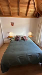 Una gran cama verde en una habitación con techos de madera. en Hermoso departamento en el centro de SMA con balcón. 4/2 en San Martín de los Andes