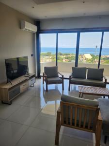 a living room with couches and a flat screen tv at SEAVIEW LUXURY APPARTMENT in Flic-en-Flac