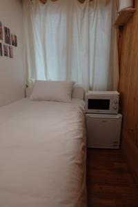 a small bedroom with a bed and a microwave at Hostel JL in Chung-jeong in Seoul