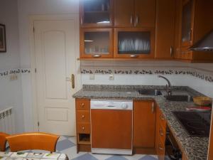 cocina con armarios de madera, fregadero y lavavajillas en LA CASA DE SENSI en Güéjar-Sierra