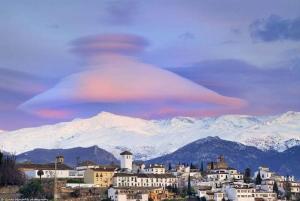 una nube lenticular sobre una ciudad con montañas cubiertas de nieve en LA CASA DE SENSI en Güéjar-Sierra