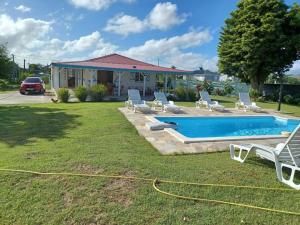 a yard with a pool with chairs and a house at La villa Rouyo in Le Moule
