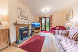 a living room with a fireplace and a tv at Roseberry Cottage Coniston in Coniston