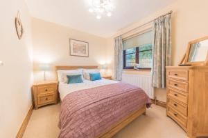 a bedroom with a bed and a dresser and a window at Roseberry Cottage Coniston in Coniston
