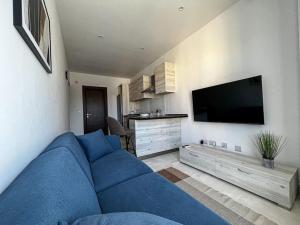 un sofá azul en la sala de estar con TV de pantalla plana en Wenza's Nest 5 min walk from St Julians en San Ġwann