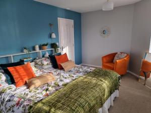 ein Schlafzimmer mit einem Bett und einem orangenen Stuhl in der Unterkunft Windrush Turret Lodge in South Cerney