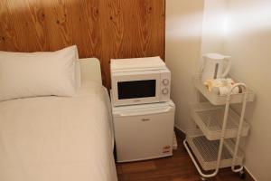 a bedroom with a bed and a microwave on a table at Hostel JL in Chung-jeong in Seoul