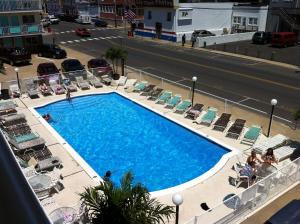a swimming pool with chairs and people sitting around it at Surfside Motel - Seaside Heights in Seaside Heights
