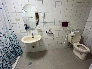 een badkamer met een toilet, een wastafel en een spiegel bij Horn Seaside Homestay in Nangan