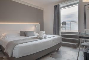 una camera con un grande letto e un balcone di Hotel Villa Ambra a Orbetello