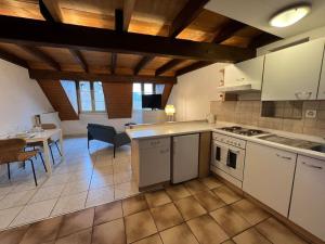 Charmant appartement en duplex à Porrentruy في بورينتري: مطبخ مع أجهزة بيضاء وغرفة طعام مع طاولة