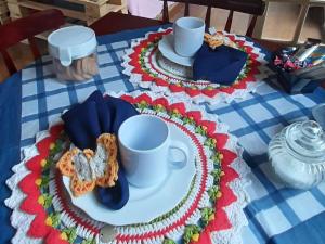 een tafel met twee borden en een beker en schotels bij Villacasamarela mini casinhas de hospedes Rio vermelho in Florianópolis