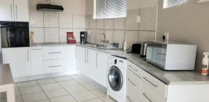 a kitchen with white cabinets and a washing machine at Feather Self Catering Accommodation in Windhoek