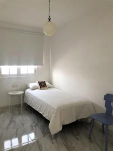 a white bedroom with a bed and a blue chair at Casa Nicolás in Playa Honda