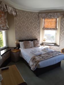 a bedroom with a large bed and two windows at Tyr Graig Castle in Barmouth