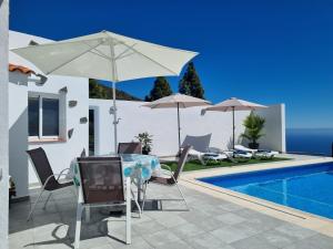 Villa con piscina y mesa con sombrilla en Casa Araviña, en Icoro
