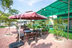 a patio with a picnic table and an umbrella at Rainbow Huts by Zing Motel in Butterworth