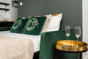 a bed with a green couch and two wine glasses at Queen Studio by LoftAffair in Krakow