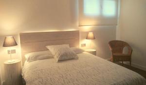 um quarto com uma grande cama branca e 2 candeeiros em Apartamento Pozozabale em Elejalde