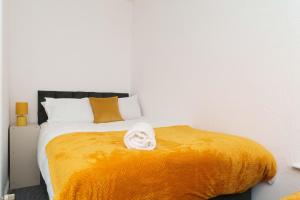 sypialnia z dużym łóżkiem i żółtym kocem w obiekcie Dent House Stays w mieście Hunslet