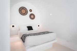 a white bedroom with a bed and a clock on the wall at AKRI santorini with heated jacuzzi in Emporio