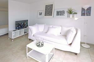 ein weißes Wohnzimmer mit einem weißen Sofa und einem TV in der Unterkunft Mare Nostrum in Maspalomas