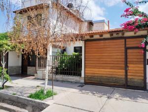 a house with a wooden garage door and a tree at LA CASA DE LA PARRA in Godoy Cruz