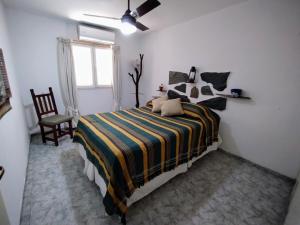 a bedroom with a bed and a chair and a window at LA CASA DE LA PARRA in Godoy Cruz