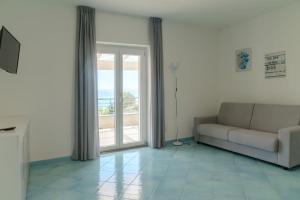 een woonkamer met een bank en een glazen schuifdeur bij L'Incanto del Golfo in Scario