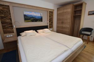 um quarto com uma grande cama branca e uma cadeira em Gästehaus Koch em Fischen
