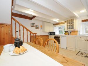 a kitchen with a table with a plate of bread on it at Henwood Barn in Liskeard