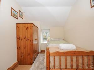 a bedroom with a bed and a wooden cabinet at Henwood Barn in Liskeard