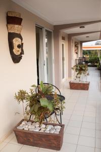 une terrasse couverte avec un banc orné de plantes et d'un masque dans l'établissement Olori Rentals, à Kampala