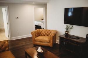 uma sala de estar com um sofá e uma cadeira e uma televisão em The Jefferson Inn em Southern Pines