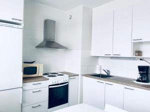 a white kitchen with a stove and a microwave at Kotimaailma Pori asunto 4 henkilölle in Pori