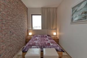 1 dormitorio con 1 cama contra una pared de ladrillo en Apartament Yellow Taxi, en Karwia
