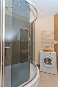 a bathroom with a shower and a washing machine at Apartament Yellow Taxi in Karwia