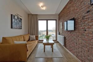 a living room with a couch and a brick wall at Apartament Yellow Taxi in Karwia