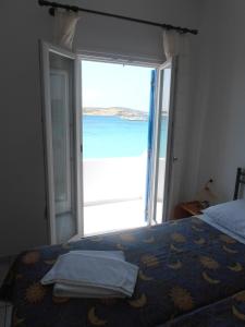 1 dormitorio con 1 cama y puerta abierta al océano en Glaros Rooms en Koufonisia