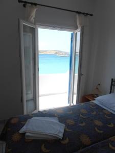 a bedroom with a bed and an open door to the ocean at Glaros Rooms in Koufonisia +17 photos