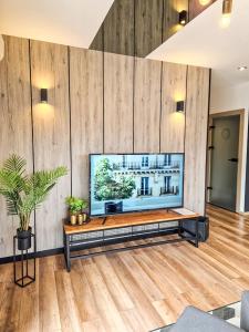 a living room with a flat screen tv on a wooden wall at Apartament LOFT in Pszczyna