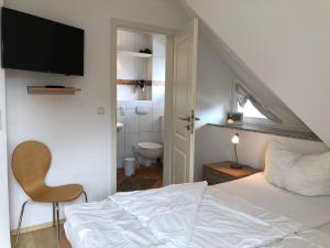 a bedroom with a white bed and a bathroom at Mine Heimat _ Dat Roeverhus_ in Zingst
