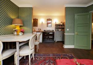 ロンドンにあるHome at Heart - Glorious 2 Bedroom Garden Apartment Notting Hill TALBの緑の壁のキッチン(テーブル、椅子付)