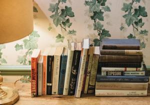 a stack of books sitting on a table next to a lamp at Home at Heart - Glorious 2 Bedroom Garden Apartment Notting Hill TALB in London