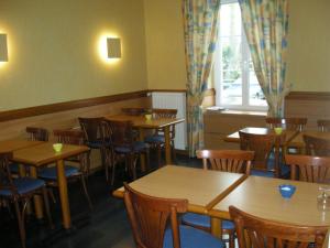 a restaurant with wooden tables and chairs and a window at Hotel La Renaissance in Cherbourg en Cotentin